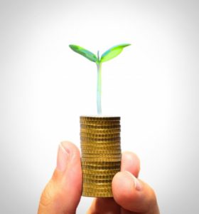 businessman holding plant sprouting from a handful of golden coin