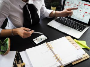 Woman in White Dress Shirt Pointing at Computer with Graphs Displayed